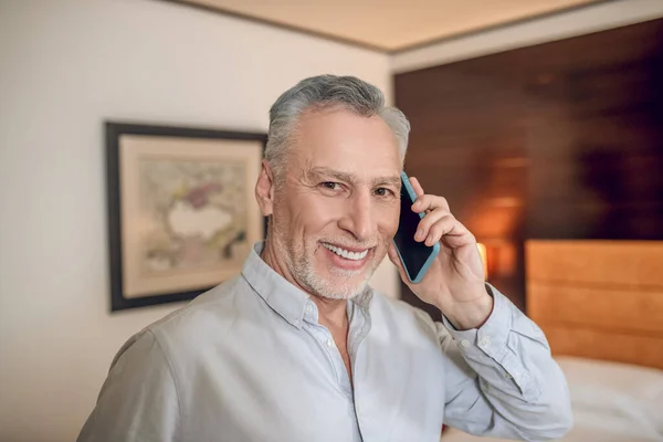 Leende medelålders gråhårig affärsman pratar i telefon och ser nöjd ut — Stockfoto