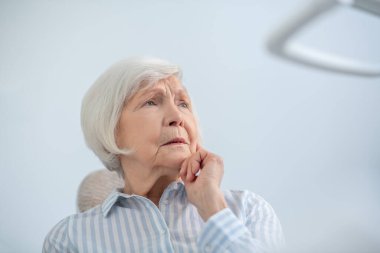 Diş ağrısından muzdarip gri saçlı bir kadının yakın çekimi.