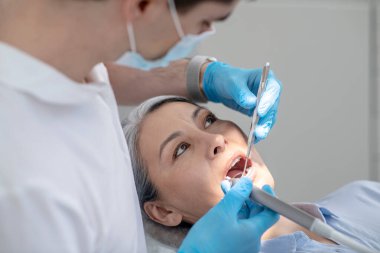 Hastalar üzerinde çalışan dişçi diş yenileme ve diş sondajı yapıyor.