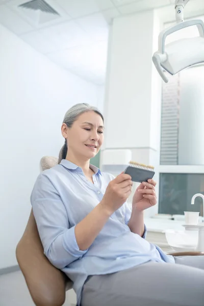 Donna seduta presso lo studio dentistico e guardando gli impianti dentali — Foto Stock