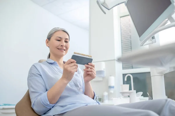 Donna seduta presso lo studio dentistico e guardando gli impianti dentali — Foto Stock