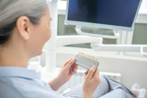 Mulher sentada no consultório de dentistas e olhando para os implantes dentários — Fotografia de Stock