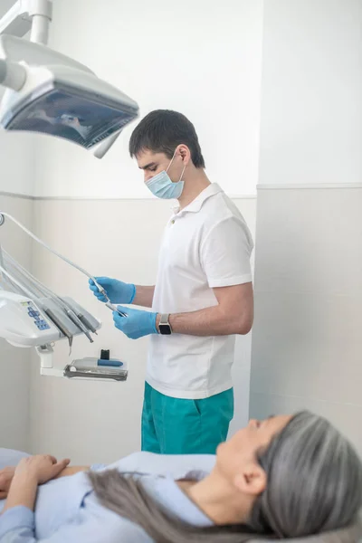 Dentista masculino em máscara protetora se preparando para a restauração dos dentes — Fotografia de Stock