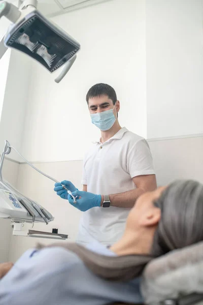 Dentista masculino em máscara protetora se preparando para a restauração dos dentes — Fotografia de Stock