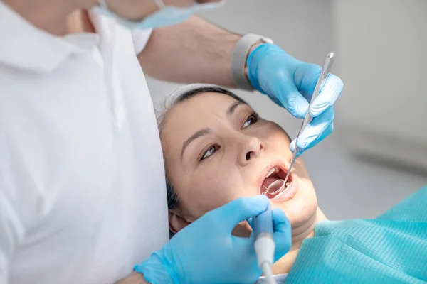 Dentista trabalhando na restauração dos dentes dos pacientes e fazendo enchimento dentário — Fotografia de Stock