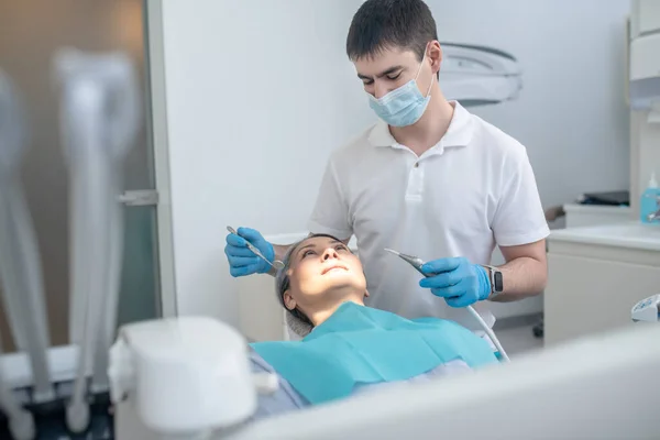 Male dentist working with a patient and making teeth restoration