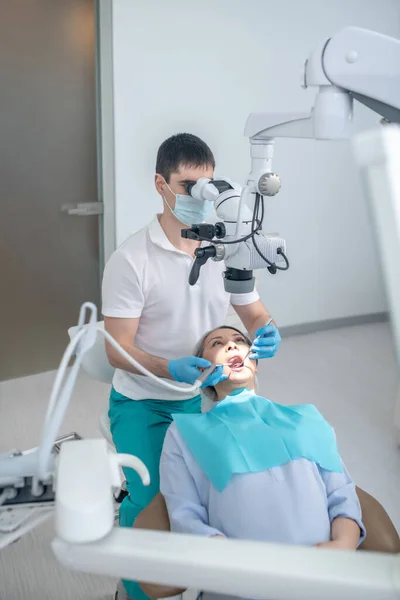 환자와 함께 일하고 광학 의료 기구를 사용하는 남성 치과 의사 — 스톡 사진