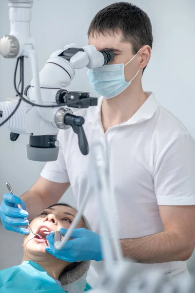 Chirurgo dentale maschile che lavora con il paziente e utilizza lo strumento medico ottico — Foto Stock