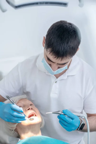 Dentista do sexo masculino que trabalha com um paciente idoso com doença periodentária — Fotografia de Stock