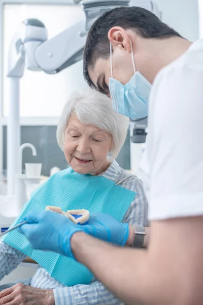 Cirurgião dentário masculino mostrando a prótese ao seu paciente — Fotografia de Stock