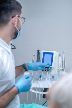 Steril eldivenli dişçi ofisinde bir hastayla çalışıyor.