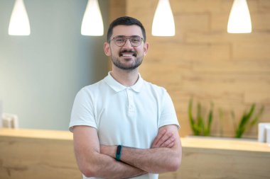 Gülümseyen koyu saçlı genç doktor kendinden emin ve pozitif görünüyor.