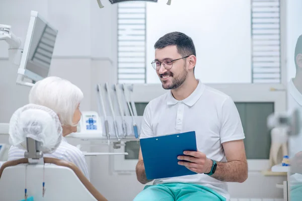 Hombre joven dentista explicando los resultados de la radiografía a su paciente femenino — Foto de Stock