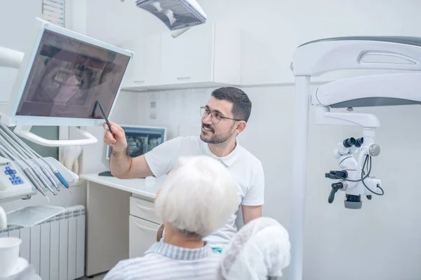 Homem jovem dentista mostrando os resultados de xray para sua paciente do sexo feminino — Fotografia de Stock