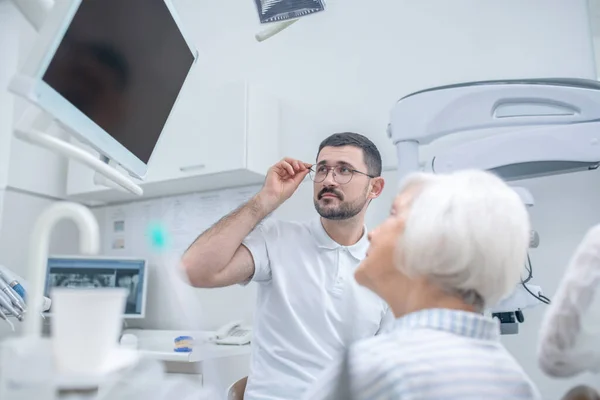 Hombre joven dentista mostrando los resultados de la radiografía a su paciente femenino — Foto de Stock