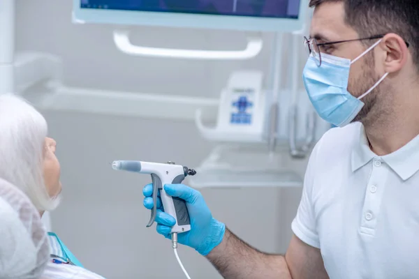 Dentista em luvas estéreis trabalhando com um paciente em seu consultório — Fotografia de Stock