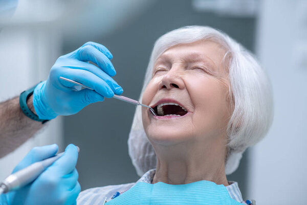 Dentist in sterile gloves working with a patient in his office