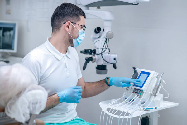 Dentist in sterile gloves working with a patient in his office