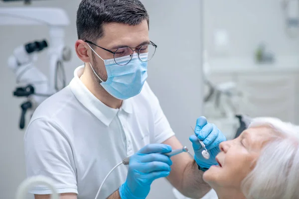 Dentista que restaura dentes ao paciente feminino sênior — Fotografia de Stock