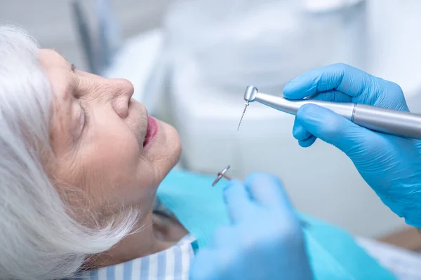 Dentista que restaura dentes ao paciente feminino sênior — Fotografia de Stock