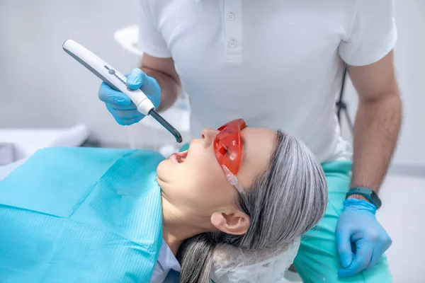 Paziente donna in occhiali protettivi con restauro dentale presso lo studio dentistico — Foto Stock