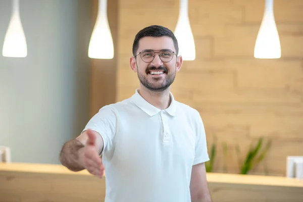 Smiling dark-haired young doctor greeting the patient and stretching his hand — Φωτογραφία Αρχείου