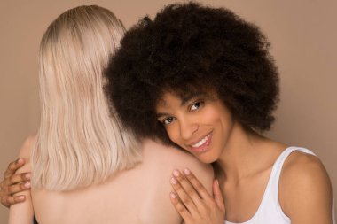 Sarışın bir kadın ve siyah saçlı bir kadın birbirlerine sarılıyorlar.