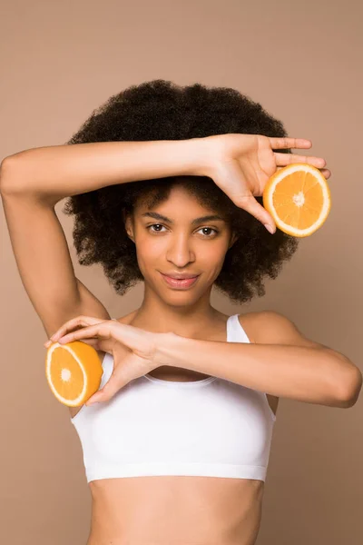 Une jeune jolie mulatta aux cheveux bouclés avec des tranches d'orange — Photo