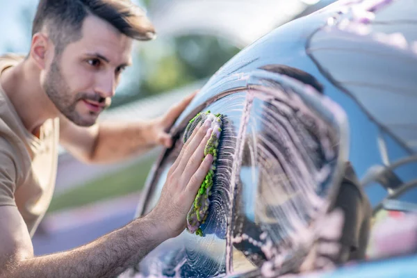 Hombre limpiando vidrio del coche con detergente — Foto de Stock