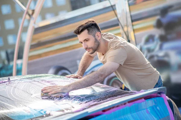 Man concentratedly washing glass of car — Stock Photo, Image