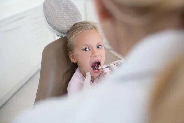 Pediadontista zkoumá zuby její roztomilé malé pacientky — Stock fotografie