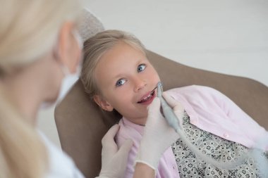 Elinde dişçi matkabı olan sarışın bir doktor ve çalışmaya hazır.
