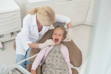 Beyaz cüppeli sarışın bir doktor küçük bir hastayla çalışıyor.