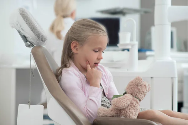 Uma menina pequena sentada na cadeira do dentista — Fotografia de Stock