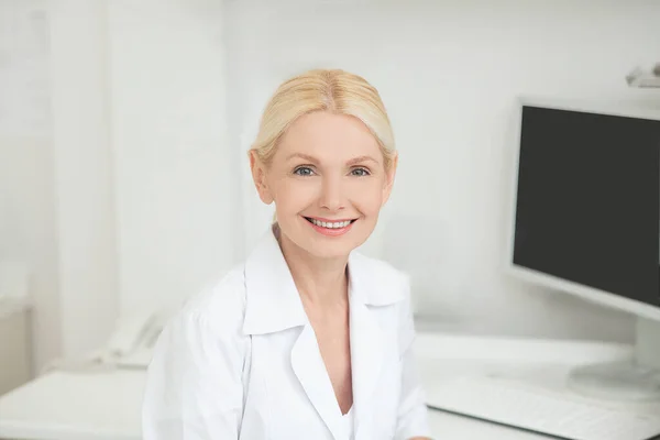 Eine blond lächelnde Frau in einem weißen Gewand — Stockfoto