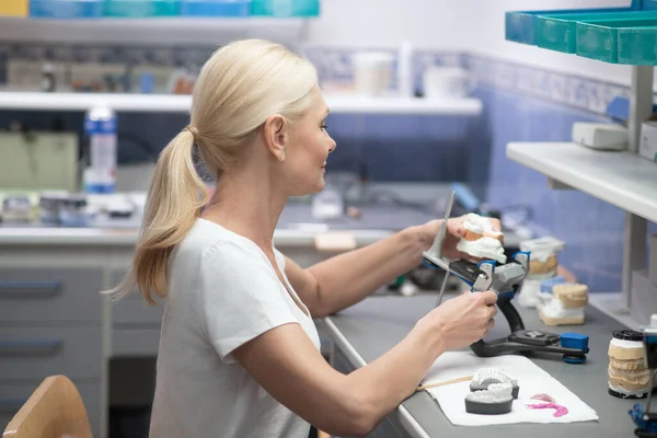 Eine Frau, die mit medizinischem Pflaster arbeitet und Zahnersatz herstellt — Stockfoto