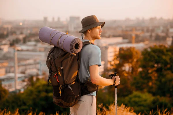 A tall man with a backpack standing on the top of the hill — Stock Photo, Image