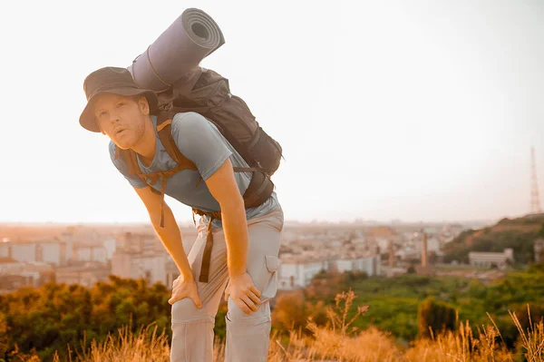 Um homem viajante com uma mochila em pé no topo da colina — Fotografia de Stock