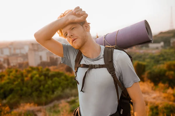 A tall man with a backpack feeling tired and exhausted — Stock Photo, Image