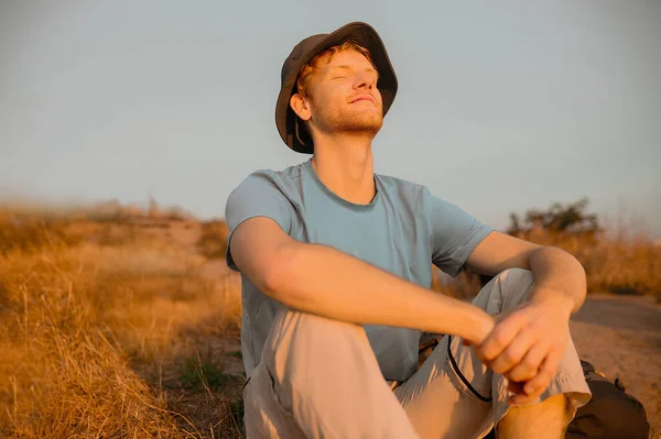 En ung man som sitter och njuter av solstrålarna — Stockfoto