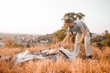 Tepede çadır kuran genç bir adam.