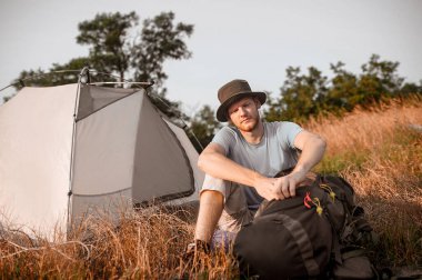 Bir adam yerde oturuyor ve çantasını topluyor.