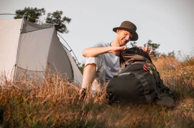 Bir adam yerde oturuyor ve çantasını topluyor.