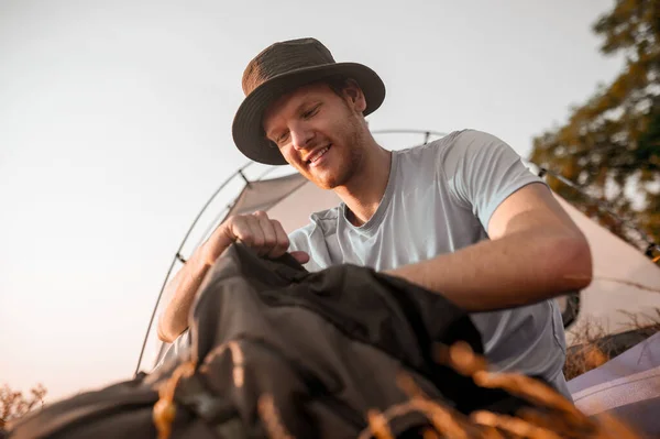 Ein Mann sitzt auf dem Boden und packt seinen Rucksack — Stockfoto