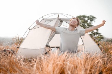 Kızıl bir adam çadırın yanında oturuyor ve uykulu ve rahat hissediyor.