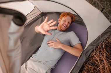 Neşeli görünen ve elini uzatan kızıl bir adam.