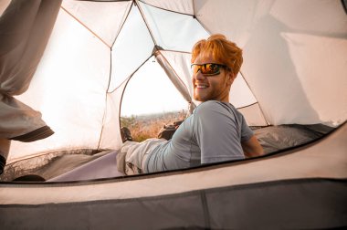 Kızıl bir adam kendini iyi hissediyor ve çadırda yatıyor.