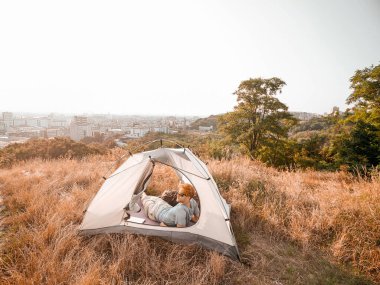 Hafta sonunu kırsalda geçiren bir adam çadırı onarmakla meşgul görünüyor.