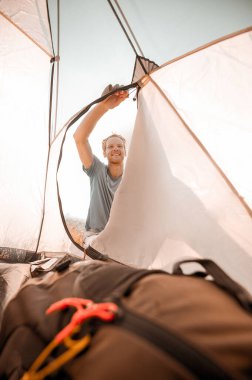 Hafta sonunu kırsalda geçiren bir adam çadırı onarmakla meşgul görünüyor.