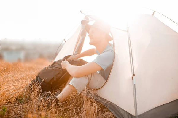 Мужчина-турист сидит рядом с палаткой и выглядит мирно — стоковое фото